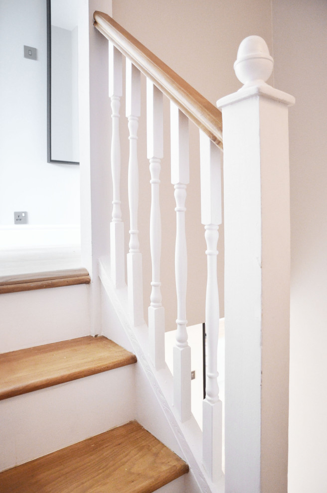 This is an example of a small traditional wood curved staircase in London with wood railing and wallpaper.