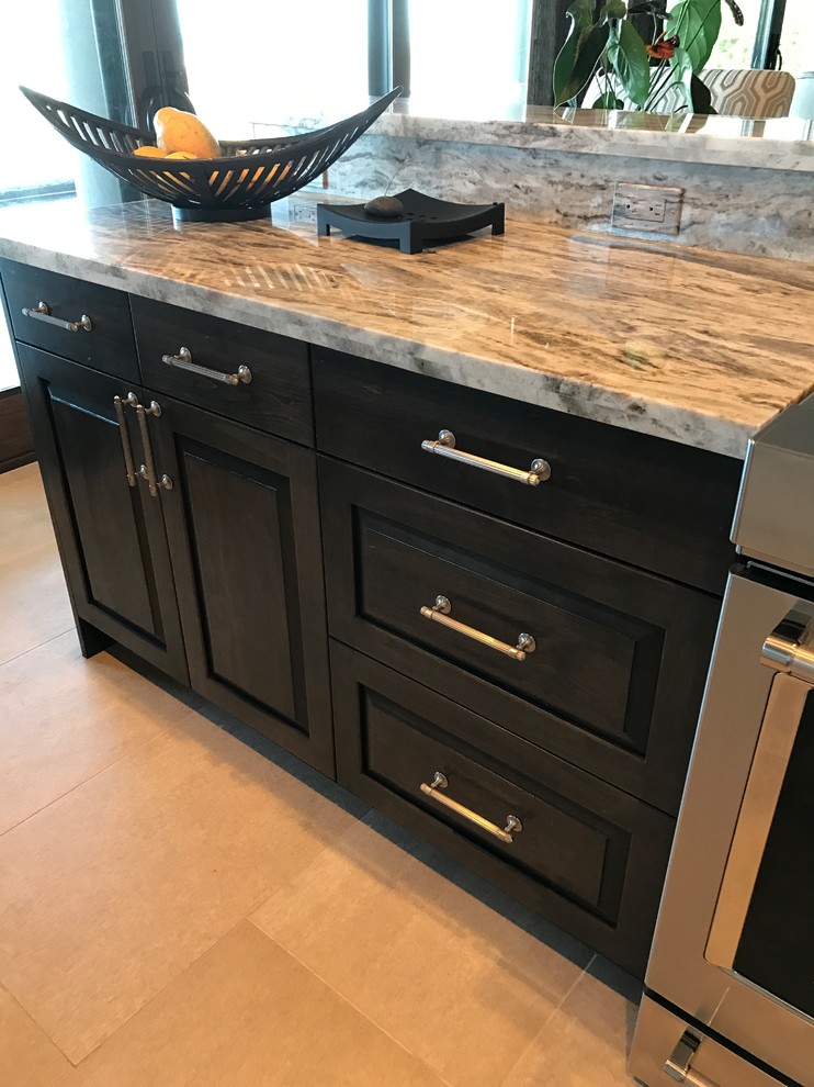 Inspiration for a large tropical galley open plan kitchen in Hawaii with an undermount sink, raised-panel cabinets, black cabinets, granite benchtops, grey splashback, stone slab splashback, stainless steel appliances, ceramic floors, with island, beige floor and grey benchtop.