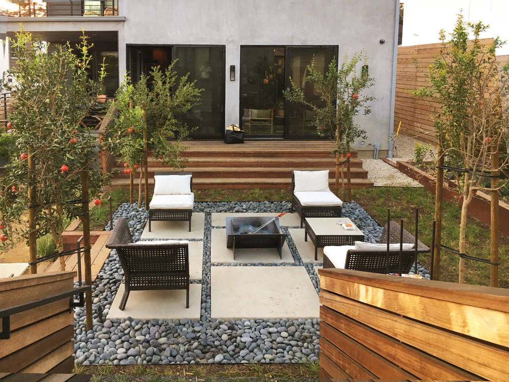 Photo of a mid-sized modern backyard full sun xeriscape for spring in Los Angeles with concrete pavers and a fire feature.