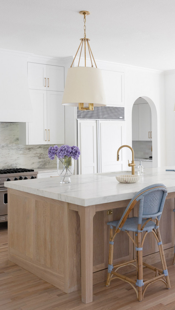 Foto på ett mycket stort vintage vit linjärt kök och matrum, med en undermonterad diskho, skåp i shakerstil, vita skåp, bänkskiva i kvartsit, vitt stänkskydd, stänkskydd i sten, rostfria vitvaror, ljust trägolv, en köksö och brunt golv