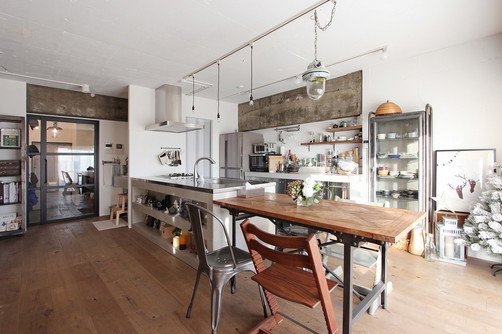 Industrial galley eat-in kitchen in Tokyo with an integrated sink, open cabinets, stainless steel appliances, light hardwood floors, a peninsula, white cabinets and stainless steel benchtops.