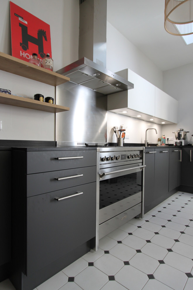 This is an example of a mid-sized contemporary l-shaped open plan kitchen in Lille with an undermount sink, beaded inset cabinets, black cabinets, granite benchtops, metallic splashback, metal splashback, stainless steel appliances, ceramic floors, no island, white floor and black benchtop.