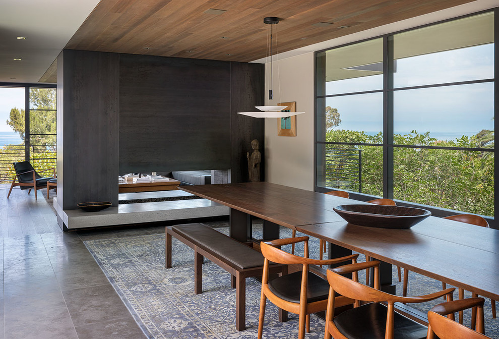 Midcentury open plan dining in Orange County with a two-sided fireplace and grey floor.