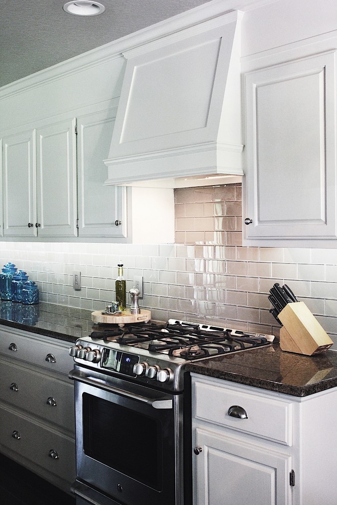 Example of a mid-sized transitional l-shaped dark wood floor and brown floor enclosed kitchen design with raised-panel cabinets, white cabinets, granite countertops, gray backsplash, glass tile backsplash, stainless steel appliances, an island and an undermount sink