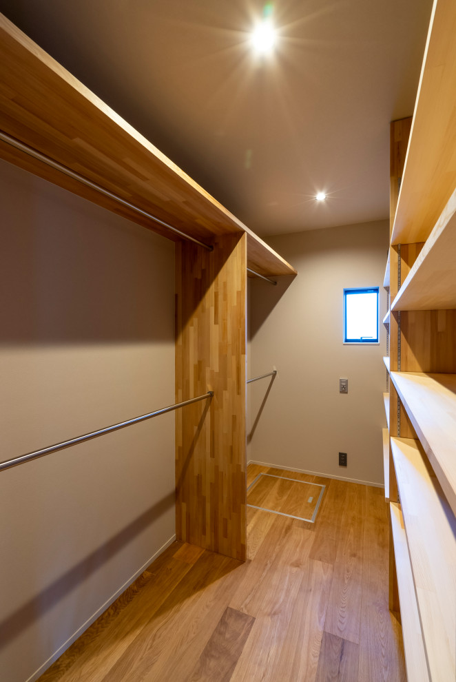 Cette photo montre un dressing moderne neutre avec un placard sans porte, des portes de placard marrons, un sol en bois brun, un sol marron et un plafond en papier peint.