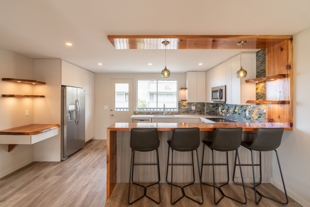 Example of a mid-sized eclectic u-shaped brown floor eat-in kitchen design with an undermount sink, flat-panel cabinets, gray cabinets, wood countertops, multicolored backsplash, ceramic backsplash, stainless steel appliances, a peninsula and brown countertops
