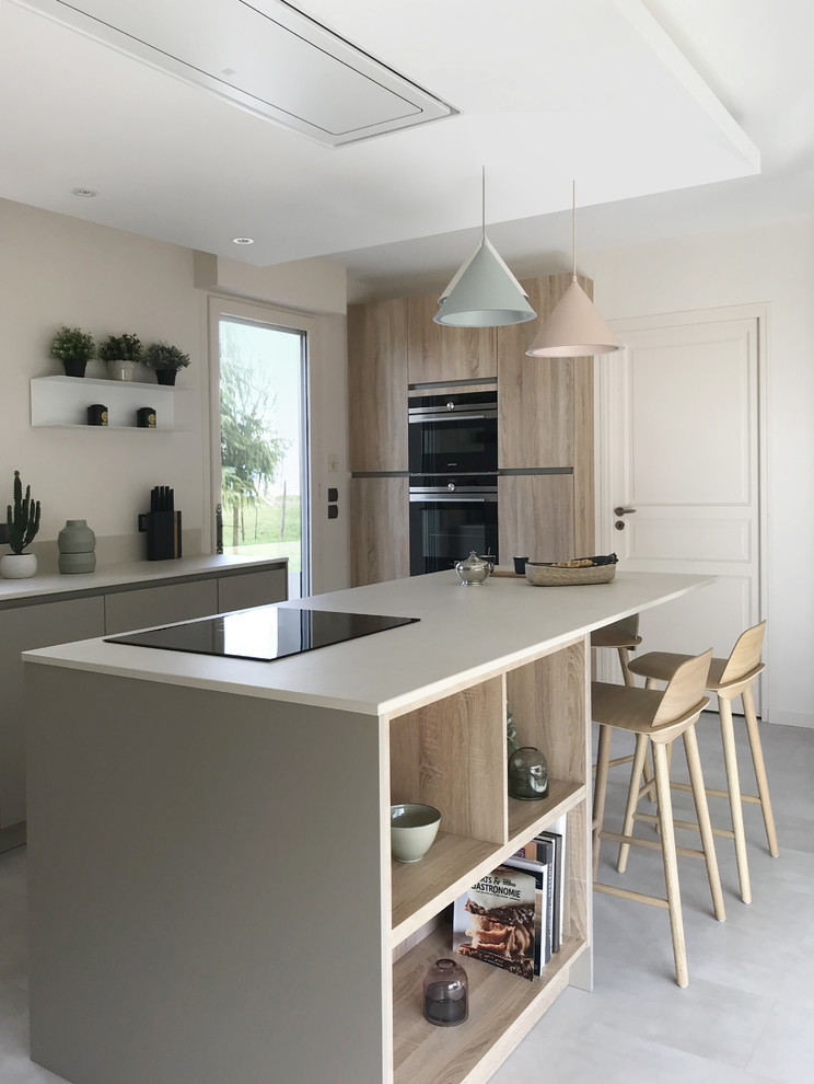Inspiration for a large contemporary kitchen in Dijon with an undermount sink, beaded inset cabinets, beige cabinets, solid surface benchtops, beige splashback, limestone splashback, black appliances, concrete floors, with island and grey floor.