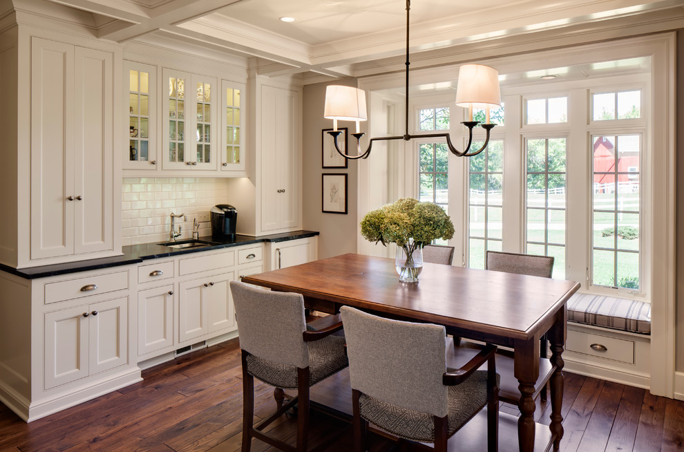 This is an example of a country dining room in Milwaukee with white walls and dark hardwood floors.