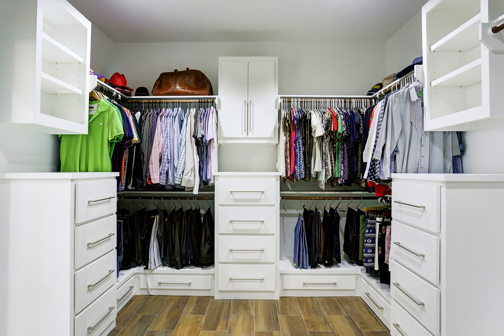 This is an example of a large contemporary gender-neutral walk-in wardrobe in Houston with flat-panel cabinets, white cabinets and medium hardwood floors.