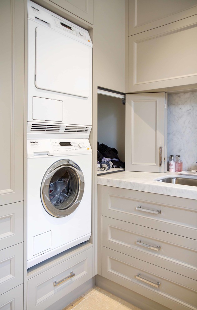 This is an example of a large traditional l-shaped laundry room in Melbourne with shaker cabinets, marble benchtops and a stacked washer and dryer.