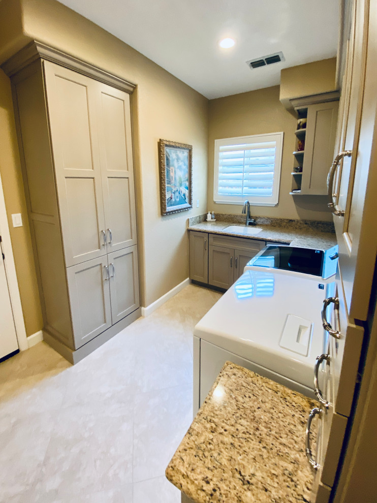 Inspiration for a mid-sized traditional u-shaped dedicated laundry room in San Francisco with an undermount sink, recessed-panel cabinets, beige cabinets, granite benchtops, beige splashback, stone slab splashback, beige walls, porcelain floors, a side-by-side washer and dryer, beige floor and beige benchtop.