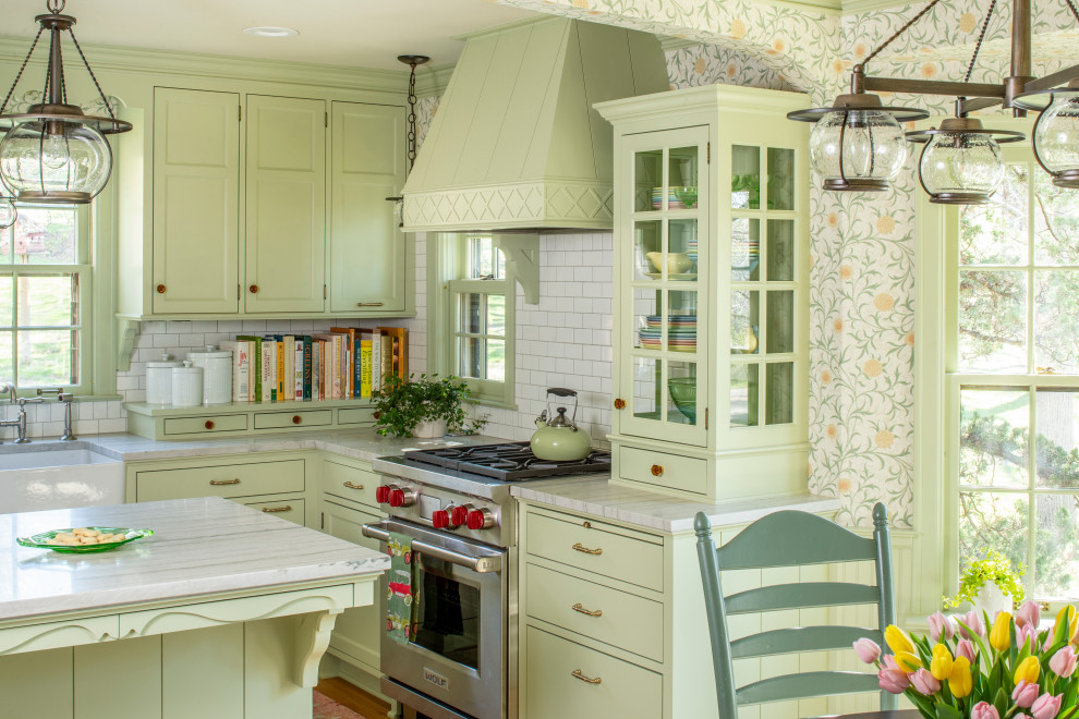 Inspiration for a traditional l-shaped kitchen in Minneapolis with a farmhouse sink, recessed-panel cabinets, green cabinets, white splashback, subway tile splashback, stainless steel appliances, medium hardwood floors, with island, brown floor and white benchtop.