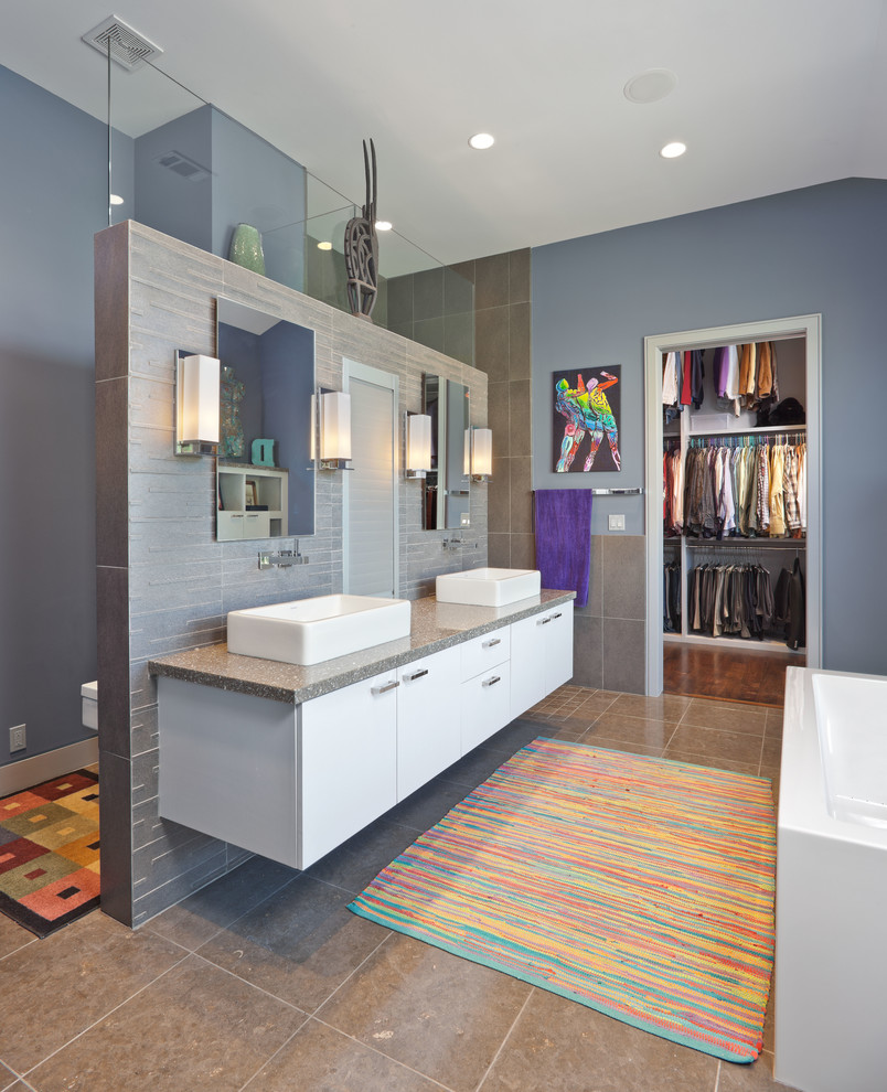 This is an example of a mediterranean bathroom in Houston with a vessel sink, flat-panel cabinets, white cabinets, a freestanding tub and gray tile.