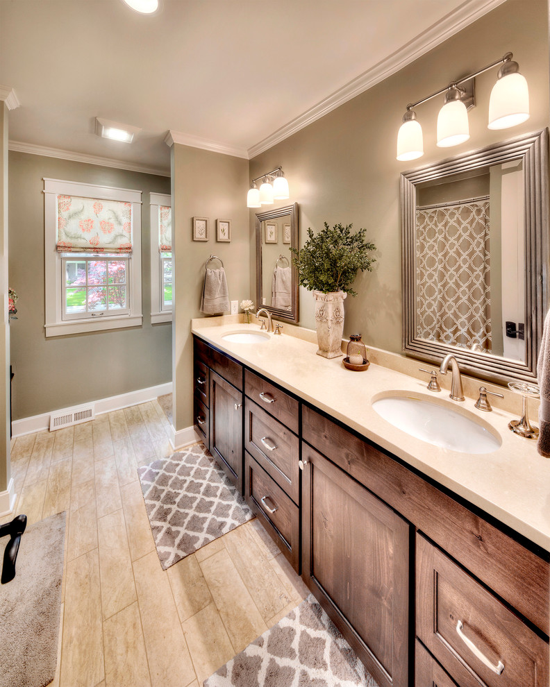 Large transitional bathroom in Kansas City with an undermount sink, recessed-panel cabinets, medium wood cabinets, solid surface benchtops, a two-piece toilet, beige tile, porcelain tile, green walls and porcelain floors.