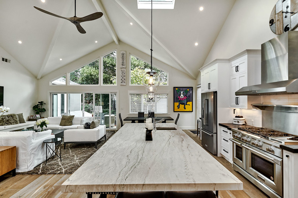 Design ideas for a large modern l-shaped open plan kitchen in San Francisco with an undermount sink, beaded inset cabinets, white cabinets, granite benchtops, white splashback, ceramic splashback, stainless steel appliances, with island, beige floor and light hardwood floors.