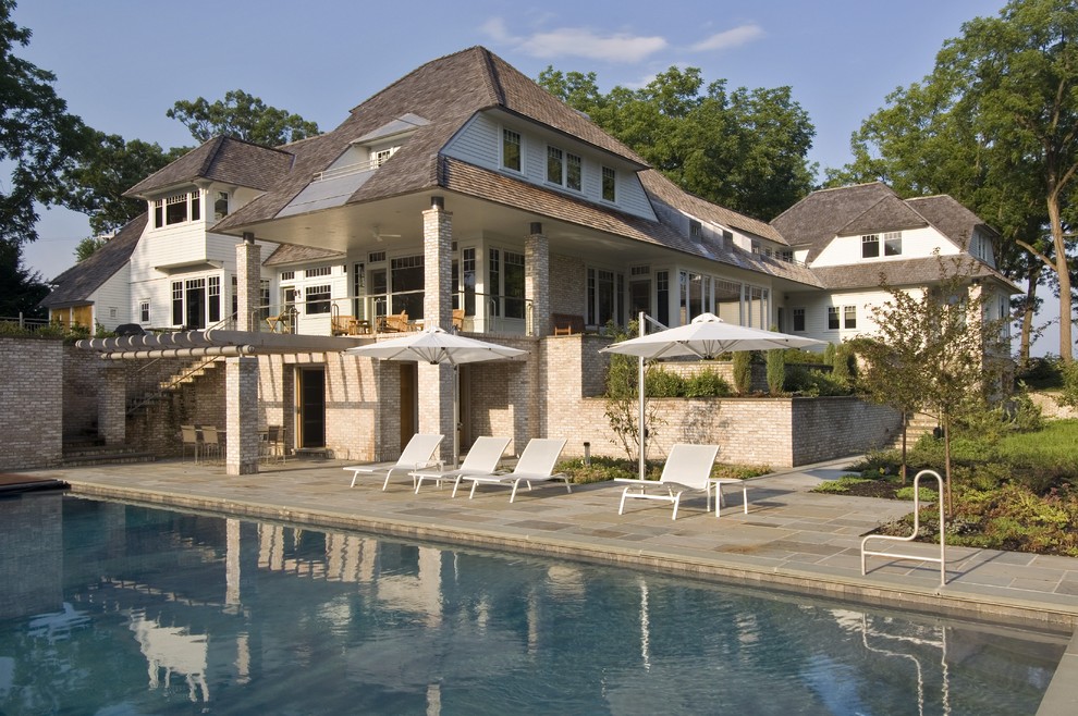 This is an example of an expansive traditional side yard rectangular lap pool in New York with natural stone pavers.