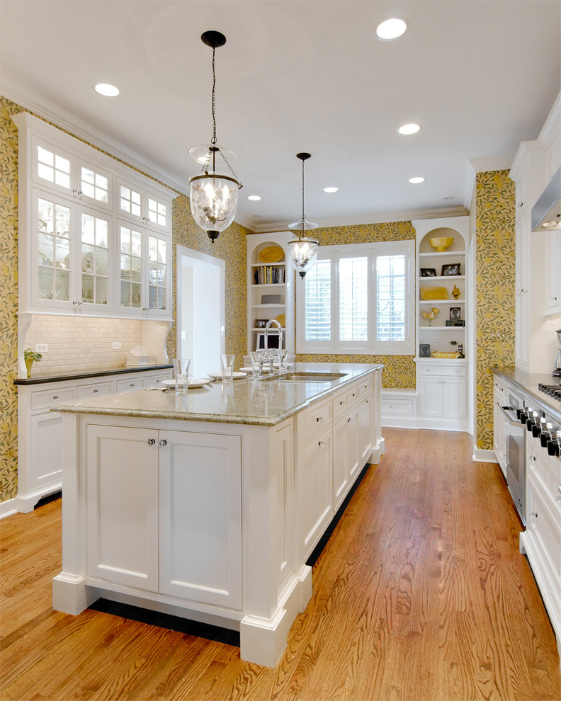 Enclosed kitchen - large transitional u-shaped medium tone wood floor enclosed kitchen idea in Chicago with an undermount sink, recessed-panel cabinets, white cabinets, white backsplash, subway tile backsplash, stainless steel appliances and an island