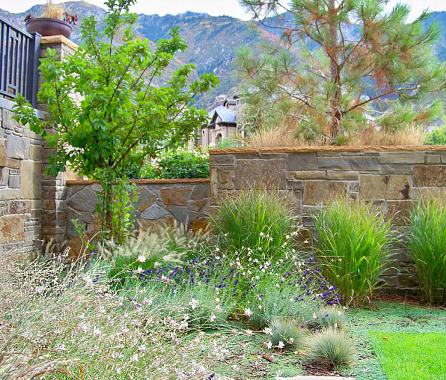 Inspiration for a mid-sized arts and crafts courtyard full sun xeriscape for summer in Salt Lake City with natural stone pavers and a retaining wall.