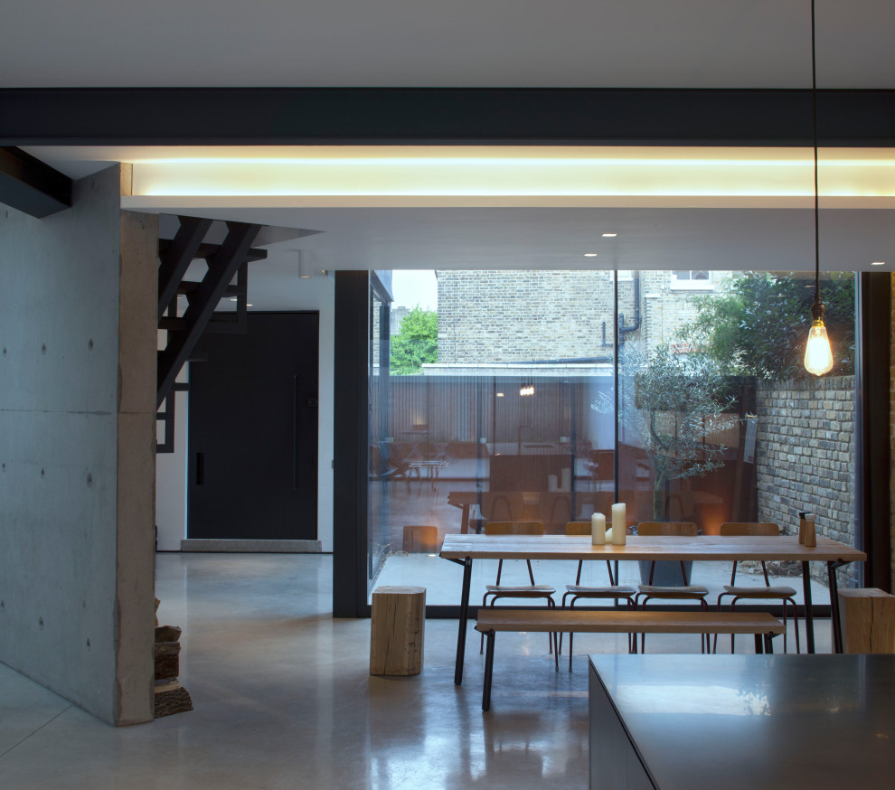 Пример оригинального дизайна: столовая в современном стиле с бетонным полом, серым полом, балками на потолке и кирпичными стенами