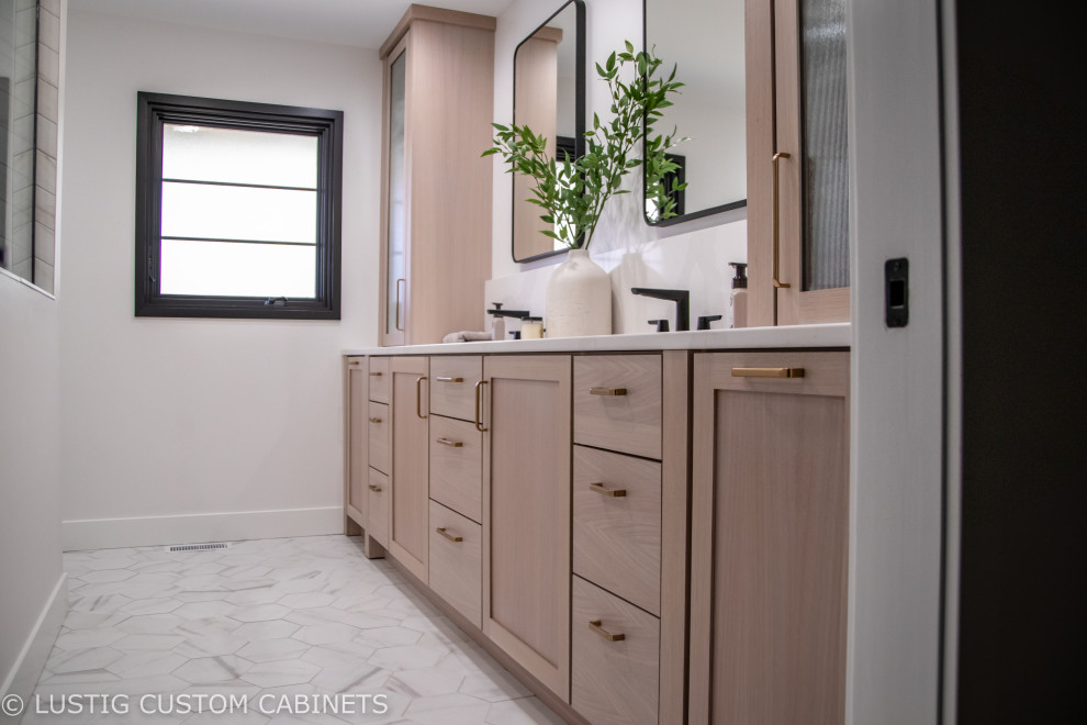 Example of a large transitional master double-sink doorless shower design with flat-panel cabinets, light wood cabinets, an undermount sink, quartz countertops, white countertops and a built-in vanity
