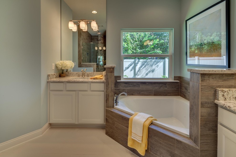 Inspiration for a mid-sized transitional master bathroom in Jacksonville with recessed-panel cabinets, white cabinets, a corner tub, a two-piece toilet, blue walls, ceramic floors, an undermount sink and granite benchtops.