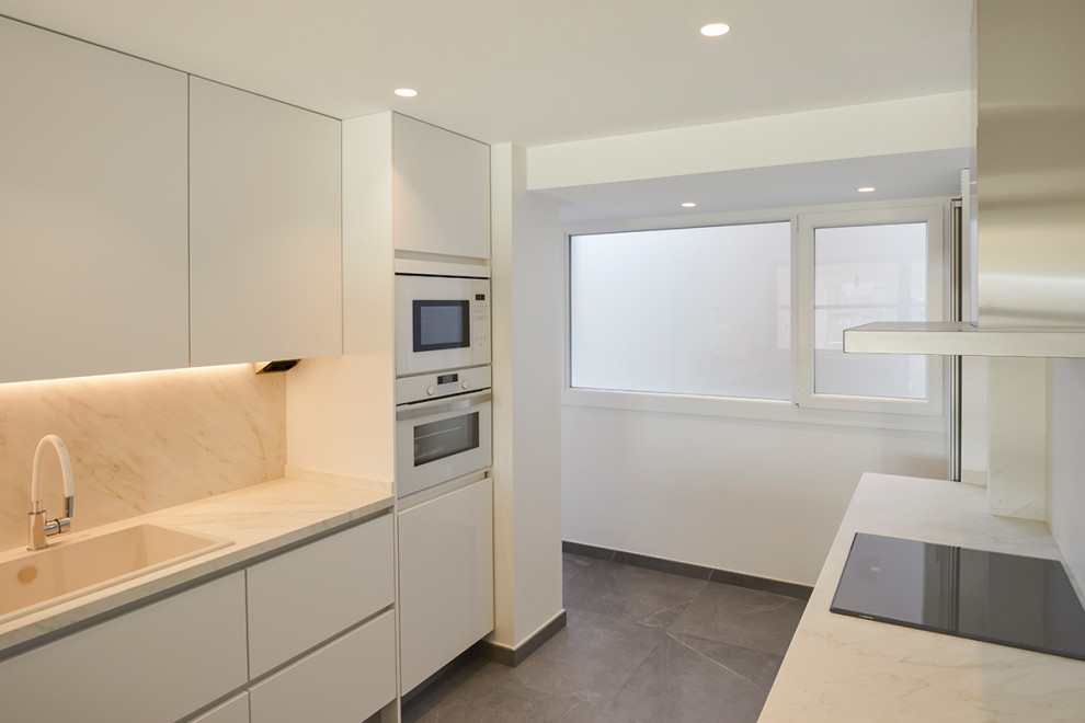 Mid-sized modern single-wall eat-in kitchen in Other with a single-bowl sink, shaker cabinets, white cabinets, quartz benchtops, white splashback, engineered quartz splashback, white appliances, porcelain floors, no island, grey floor and white benchtop.