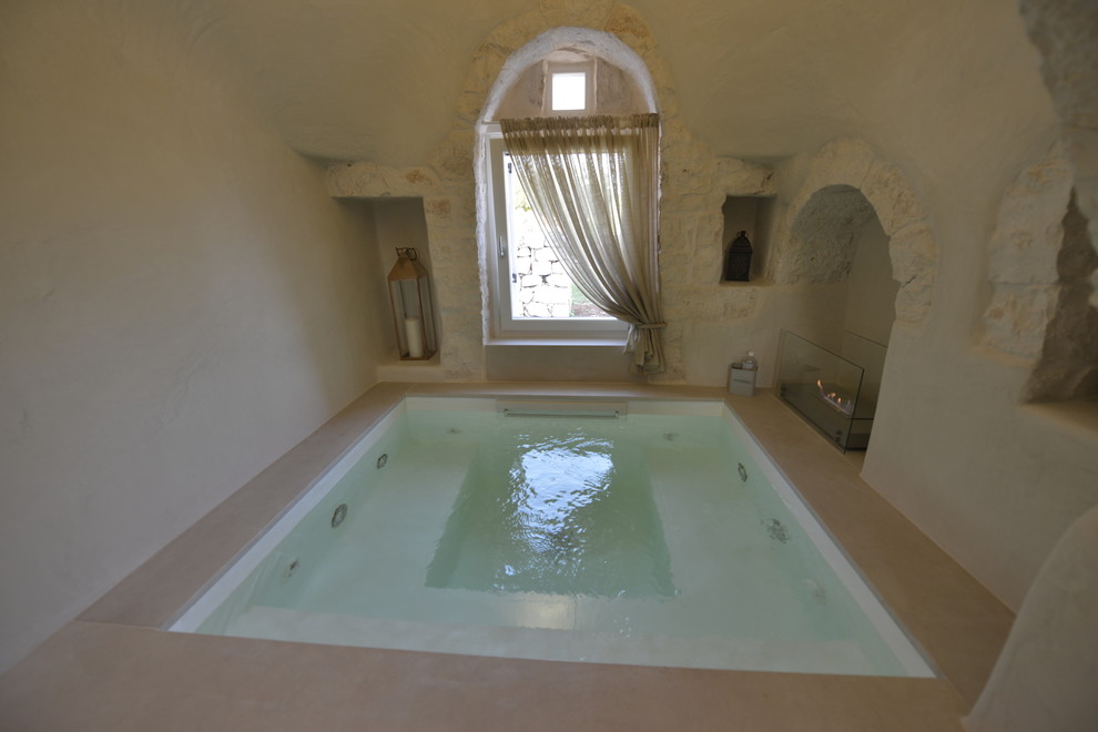 Small country indoor custom-shaped pool in Bari with a hot tub and natural stone pavers.