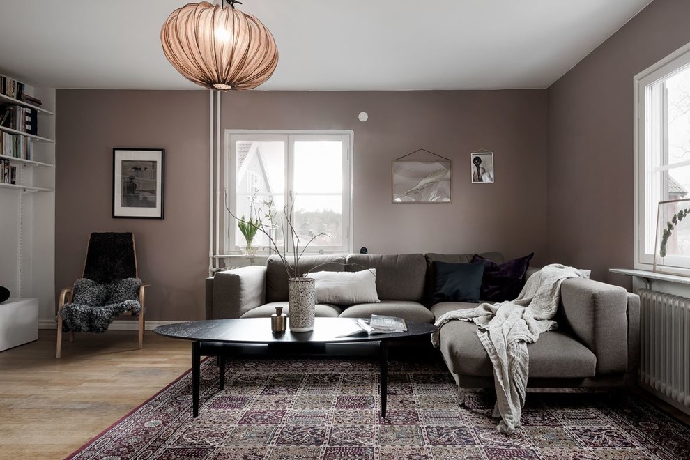 Scandinavian enclosed living room in Stockholm with medium hardwood floors, brown floor and brown walls.