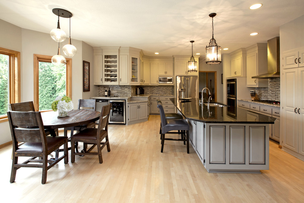 Design ideas for a mid-sized transitional u-shaped eat-in kitchen in Minneapolis with a drop-in sink, raised-panel cabinets, beige cabinets, laminate benchtops, grey splashback, glass tile splashback, stainless steel appliances, light hardwood floors and with island.