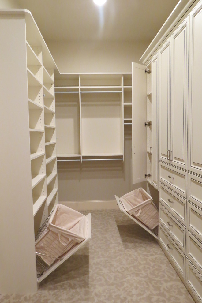 This is an example of a large traditional women's walk-in wardrobe in Atlanta with raised-panel cabinets, carpet and white cabinets.