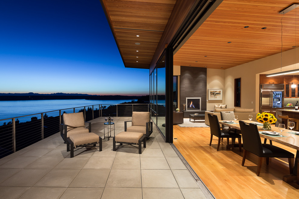 Photo of a large contemporary backyard deck in Seattle with a roof extension.