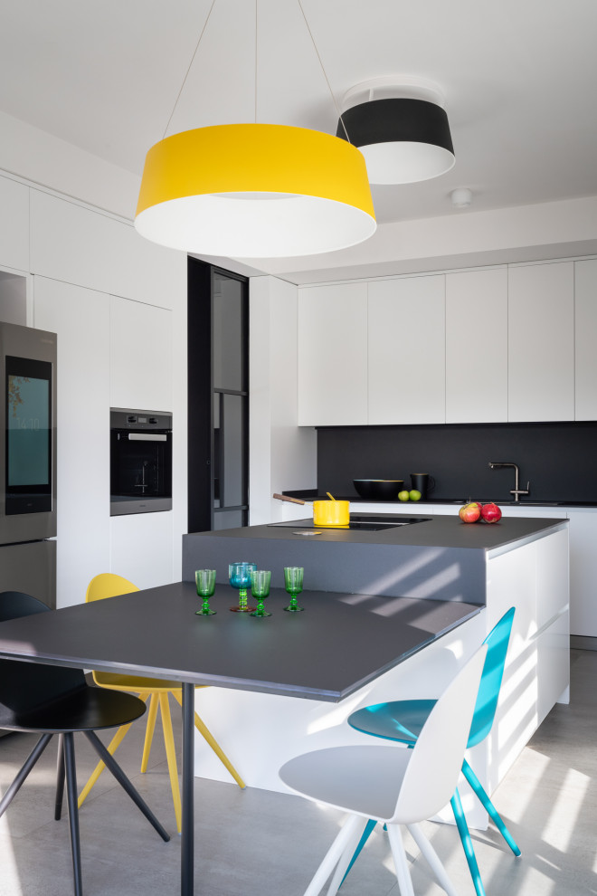 Photo of a contemporary u-shaped eat-in kitchen in Florence with flat-panel cabinets, white cabinets, stainless steel appliances, with island, grey floor and black benchtop.
