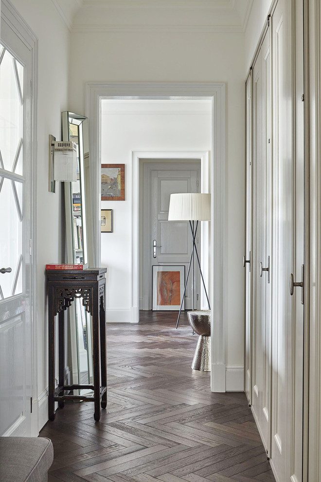 This is an example of a traditional hallway in Moscow with white walls and dark hardwood floors.