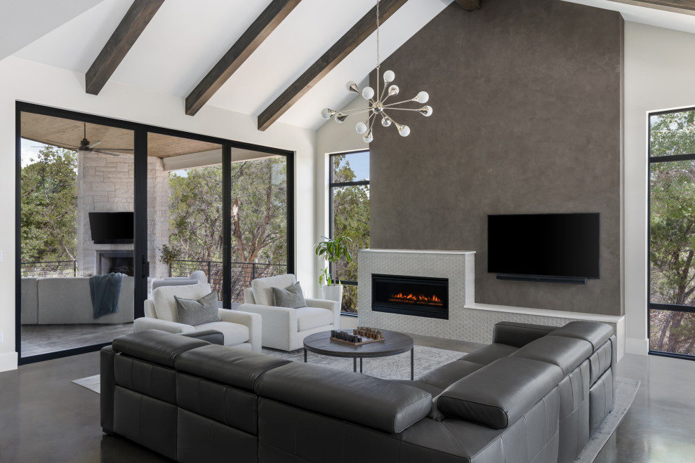 Contemporary open concept living room in Austin with white walls, concrete floors, a standard fireplace, a wall-mounted tv, grey floor, exposed beam and vaulted.