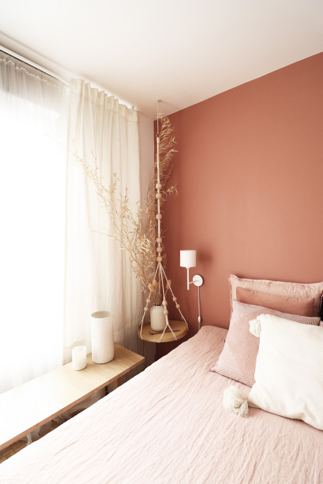 Cette image montre une chambre parentale bohème de taille moyenne avec un mur rose et un sol en bois brun.