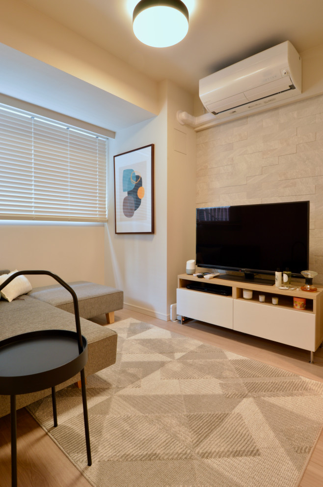 Bild på ett litet funkis allrum med öppen planlösning, med vita väggar, ljust trägolv och en fristående TV