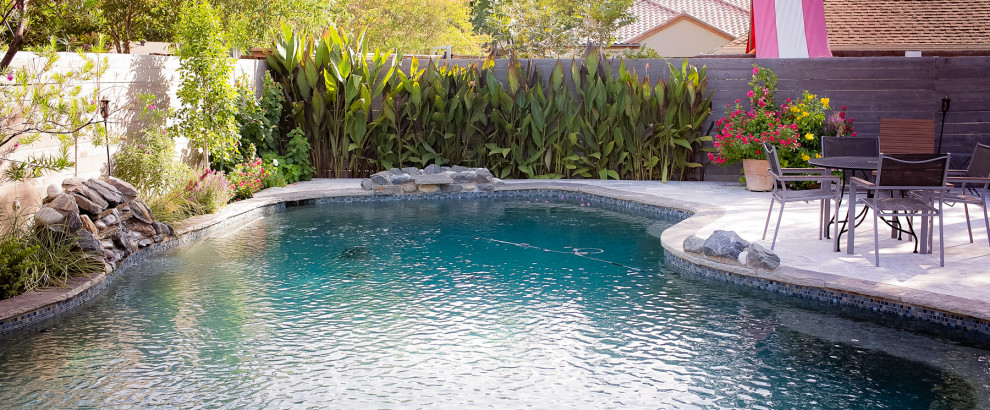 Modelo de piscina retro tipo riñón en patio trasero con paisajismo de piscina y adoquines de piedra natural