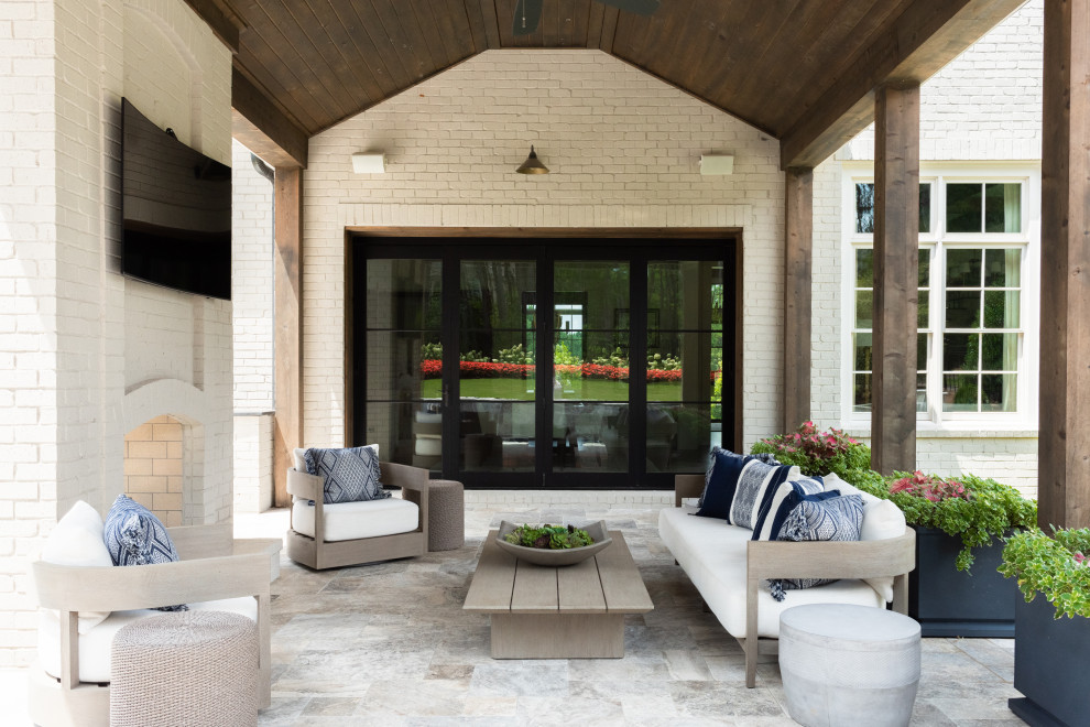 Idée de décoration pour une grande terrasse arrière design avec une cheminée et des pavés en pierre naturelle.