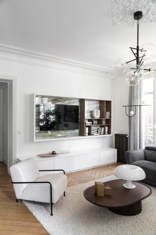 This is an example of a mid-sized contemporary enclosed family room in Paris with a library, white walls, light hardwood floors, no fireplace, a built-in media wall and brown floor.