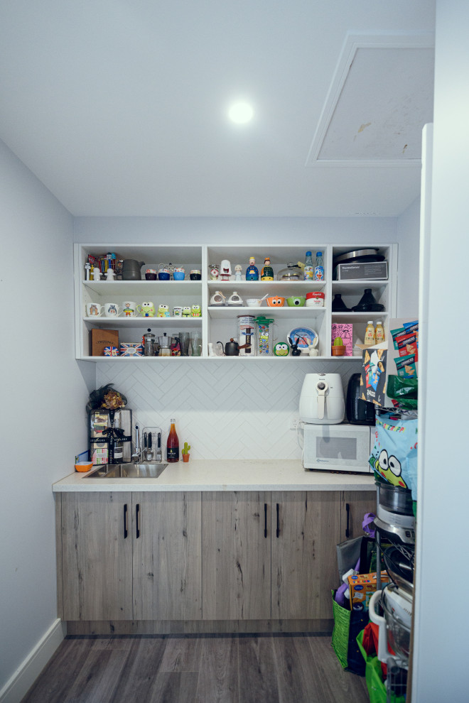 This is an example of a mid-sized contemporary galley eat-in kitchen in Melbourne with an undermount sink, flat-panel cabinets, white cabinets, quartz benchtops, white splashback, linoleum floors, with island and white benchtop.