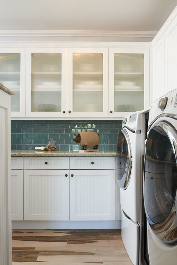Design ideas for a mid-sized eclectic l-shaped utility room in Los Angeles with shaker cabinets, white cabinets, quartzite benchtops, white walls, medium hardwood floors and a side-by-side washer and dryer.