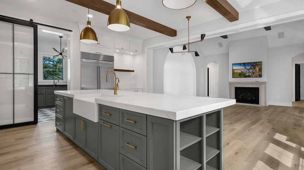 Example of a transitional u-shaped exposed beam eat-in kitchen design in Columbus with a farmhouse sink, shaker cabinets, green cabinets, quartz countertops, white backsplash, subway tile backsplash, stainless steel appliances, an island and white countertops