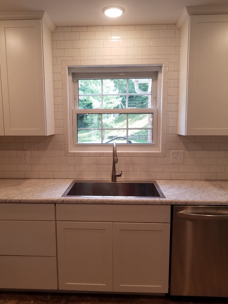 Mid-sized transitional l-shaped vinyl floor and beige floor eat-in kitchen photo in Cincinnati with a single-bowl sink, shaker cabinets, white cabinets, laminate countertops, white backsplash, porcelain backsplash, stainless steel appliances and no island
