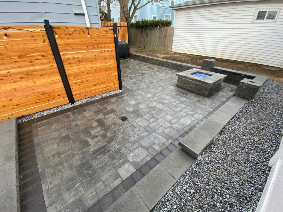 Photo of a mid-sized traditional backyard patio in New York with a fire feature, concrete pavers and no cover.