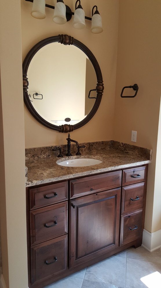 Design ideas for a large traditional master bathroom in Other with an undermount sink, raised-panel cabinets, dark wood cabinets, granite benchtops, a drop-in tub, an alcove shower, a one-piece toilet, beige tile, porcelain tile, beige walls and porcelain floors.