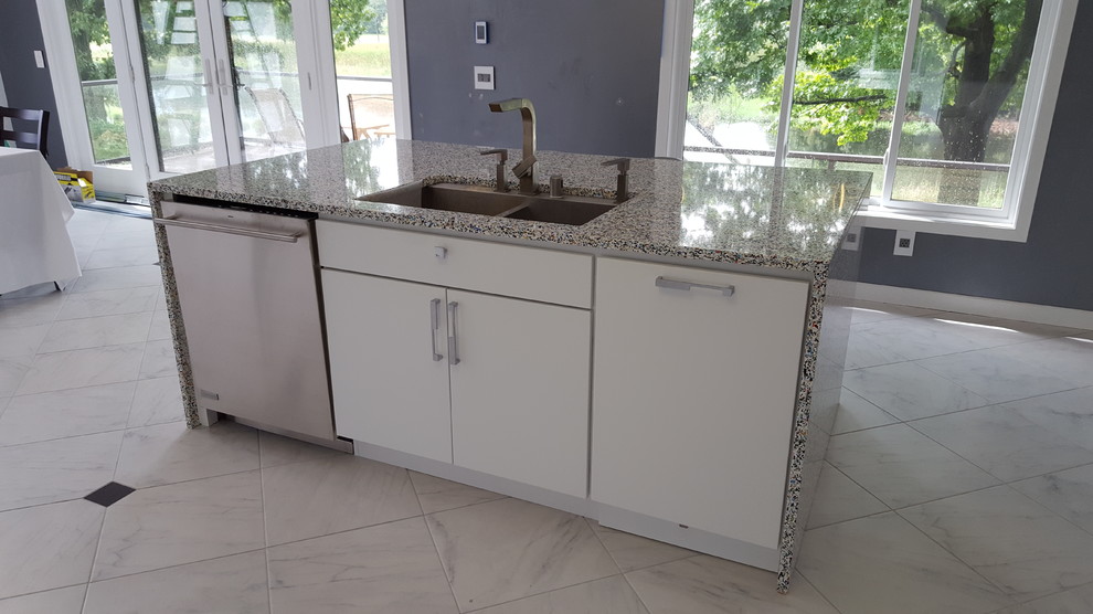 Photo of a large modern single-wall eat-in kitchen in Minneapolis with flat-panel cabinets, white cabinets, white splashback, stainless steel appliances, with island, a double-bowl sink, terrazzo benchtops, porcelain floors and white floor.