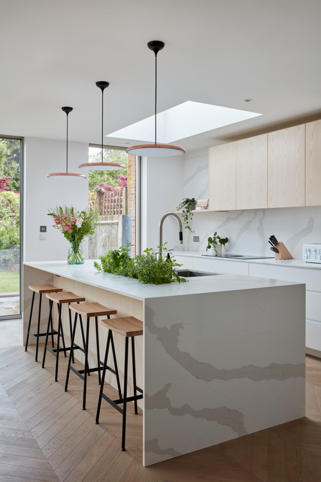Example of a large danish l-shaped kitchen design in London with flat-panel cabinets, white cabinets, quartzite countertops, white backsplash, an island and white countertops