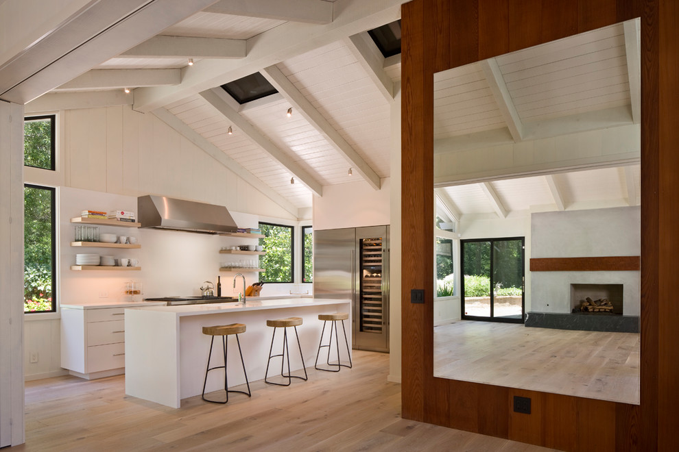 Design ideas for a large midcentury l-shaped open plan kitchen in Other with flat-panel cabinets, white cabinets, quartz benchtops, stainless steel appliances, light hardwood floors, with island and brown floor.