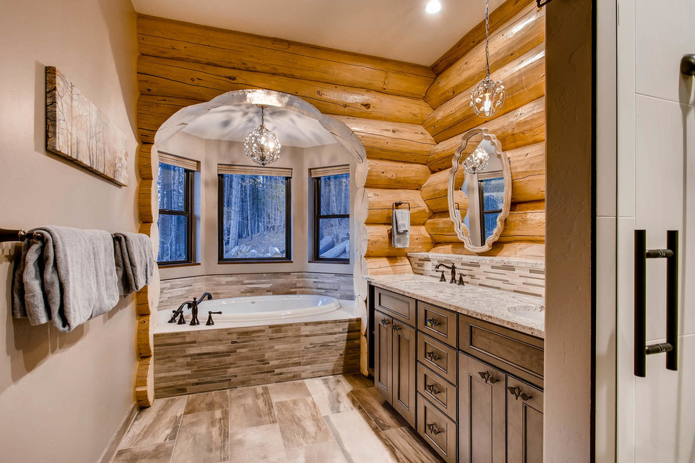 Inspiration for a mid-sized country master bathroom in Denver with ceramic floors, an undermount sink, granite benchtops, recessed-panel cabinets, dark wood cabinets, a drop-in tub, multi-coloured tile and matchstick tile.