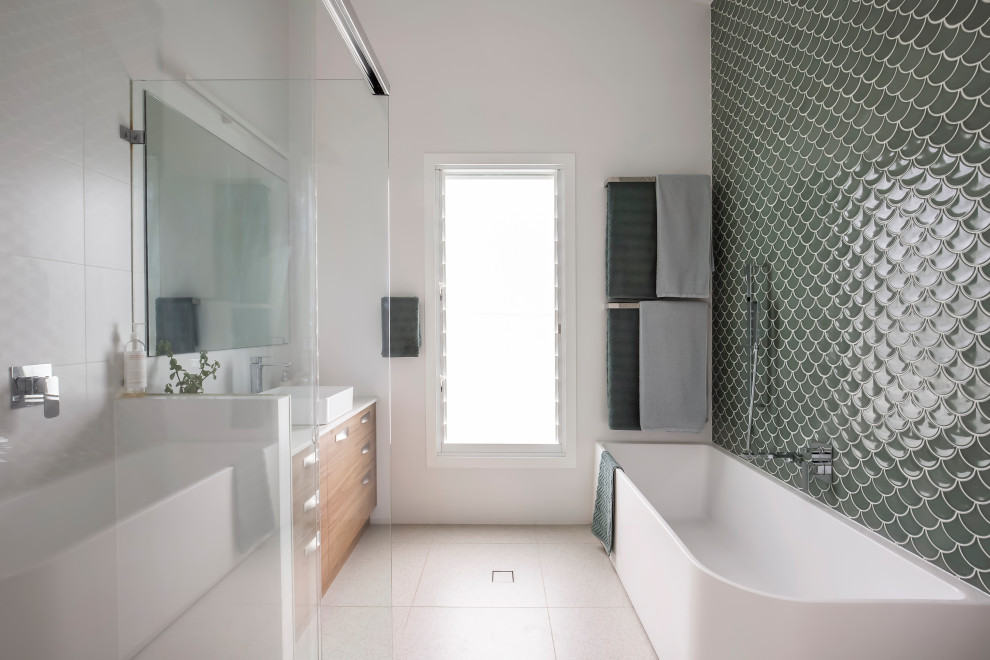 This is an example of a mid-sized contemporary master bathroom in Sydney with flat-panel cabinets, medium wood cabinets, a corner tub, a corner shower, green tile, porcelain tile, white walls, porcelain floors, a console sink, engineered quartz benchtops, beige floor, a sliding shower screen, white benchtops, a single vanity, a freestanding vanity, vaulted and planked wall panelling.